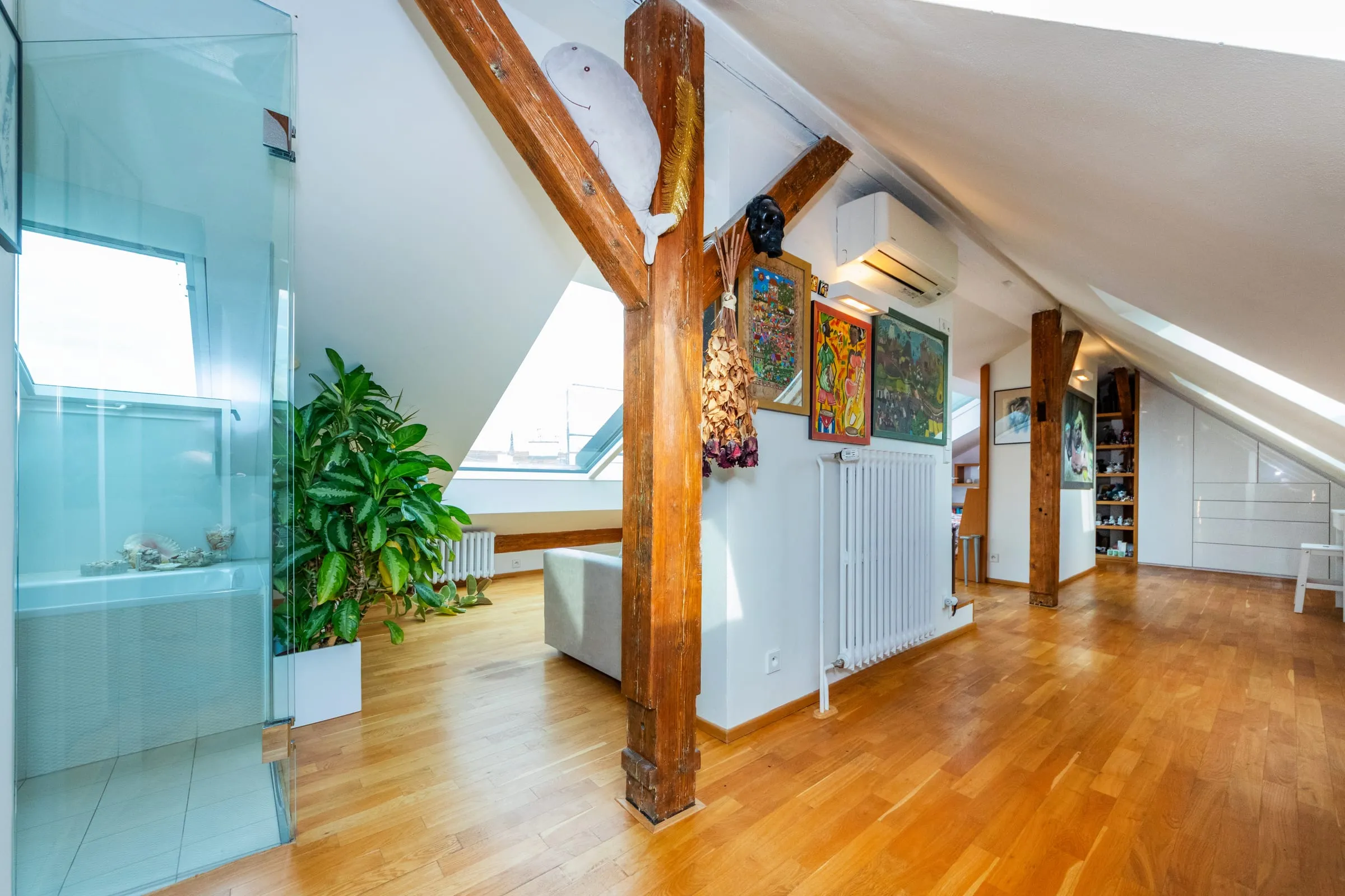 Upstairs living area with timber beams, plants and a glass shower wall